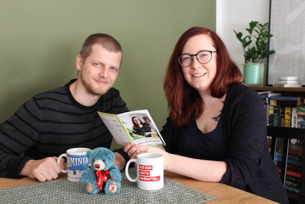 Johanna Verhoven und ihr Mann Simon sitzen am Küchentisch und betrachten den Folder zum Welt Aids Tag 2020